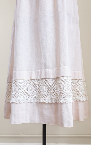 pink dress with lace trim on a mannequin against a beige wall