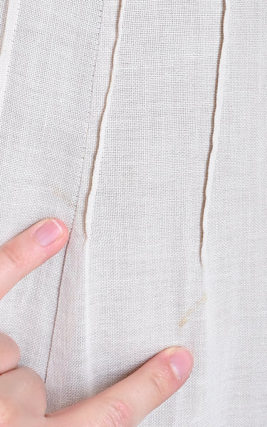 Close-up of a hand holding fabric with a visible thread pull, on a light background