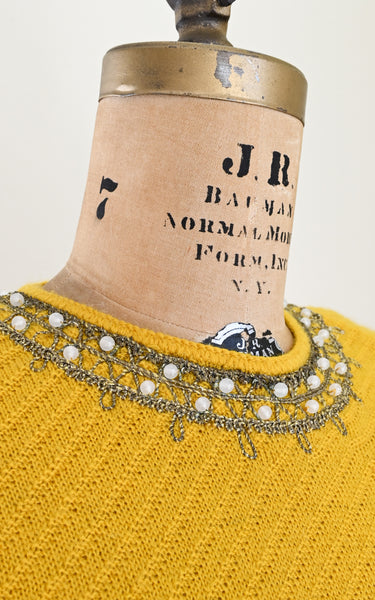 Yellow vintage sweater with decorative neckline on a mannequin with 'J.R.' label.